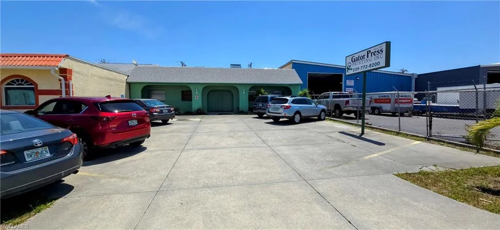 View of building exterior with uncovered parking and fence