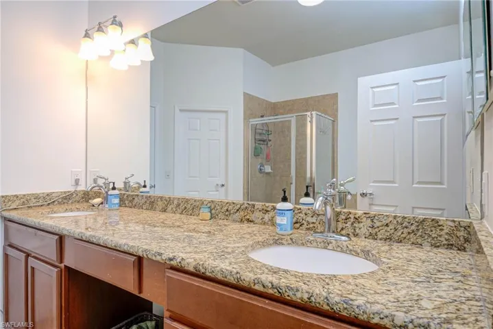 Full bathroom featuring a stall shower, a sink, and double vanity