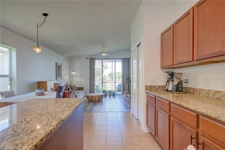 Kitchen with open floor plan, light tile patterned floors, pendant lighting, and light stone countertops