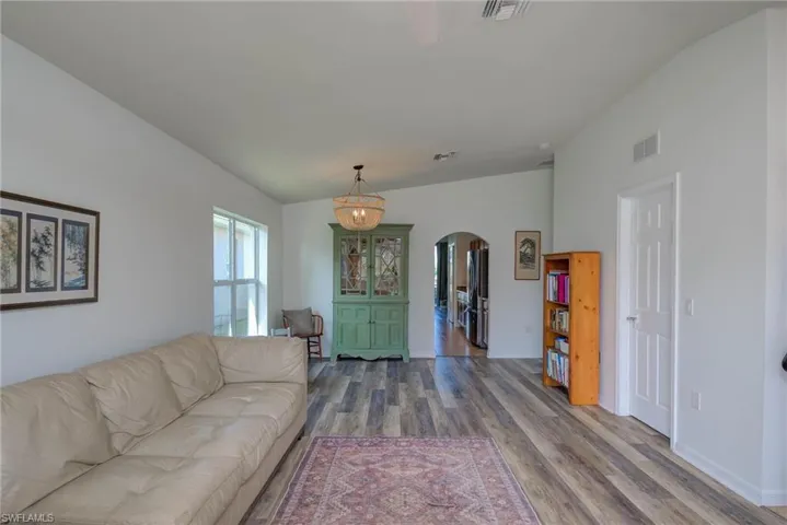 Living room with arched walkways, visible vents, and wood finished floors