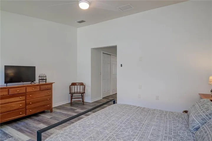 Bedroom featuring a ceiling fan, visible vents, baseboards, and wood finished floors