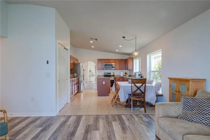 Living area with visible vents, arched walkways, light wood-style flooring, vaulted ceiling, and recessed lighting