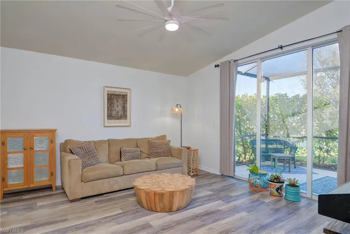 Living area featuring light wood finished floors, ceiling fan, baseboards, and vaulted ceiling