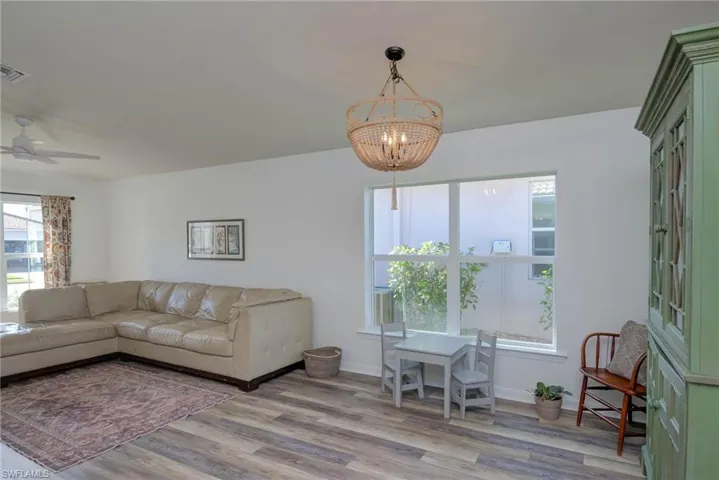 Living room featuring light wood finished floors, visible vents, baseboards, and ceiling fan with notable chandelier