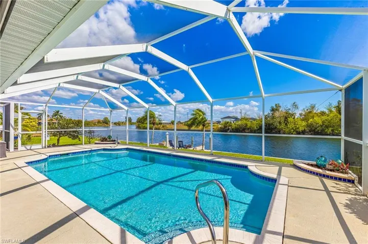Outdoor pool featuring a screen enclosure, a patio, and a water view