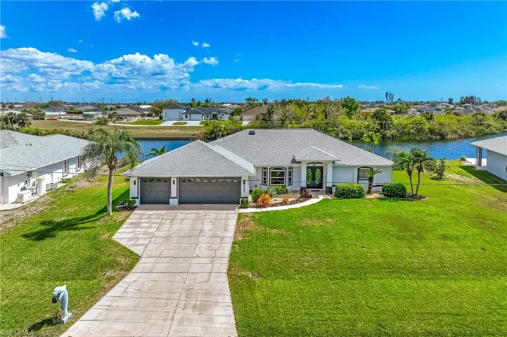 Ranch-style house with an attached garage, a front yard, a water view, driveway, and a residential view