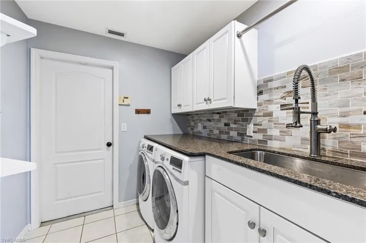 Laundry area with washer and clothes dryer and light tile patterned floors