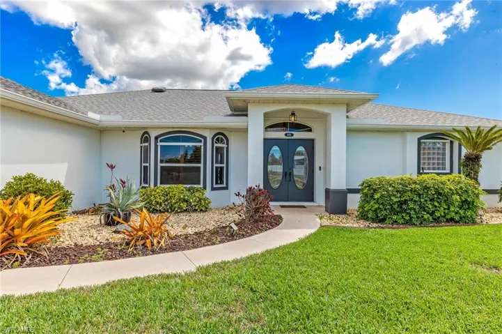Property entrance with roof with shingles, stucco siding, a lawn, and french doors
