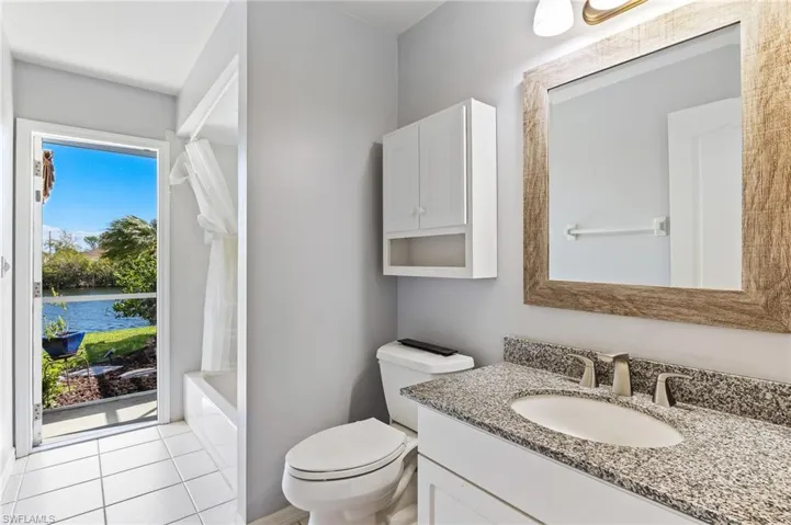 Bathroom with vanity, a water view, shower / bath combo, and light tile patterned floors