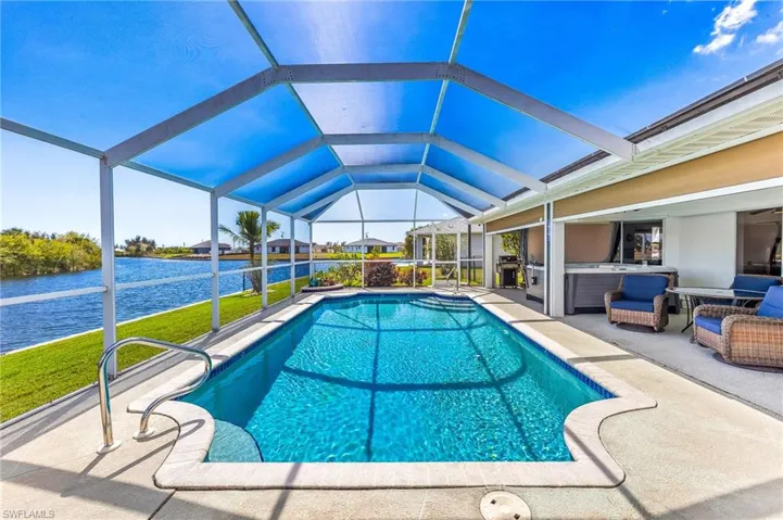 Swimming pool featuring a sunroom, a lanai, a patio, a hot tub, and grilling area