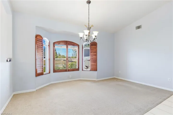Dining room with vaulted ceiling, light carpet, and a chandelier