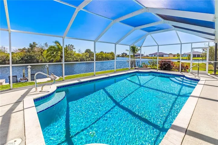 Swimming pool with a sunroom, a lanai, a water view, and a patio area