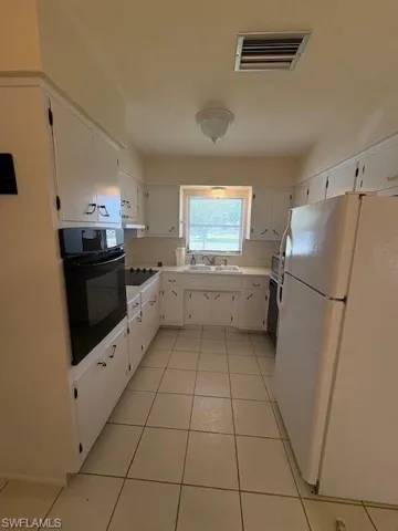 Kitchen with wall oven, cooktop, visible vents, fridge, and a sink