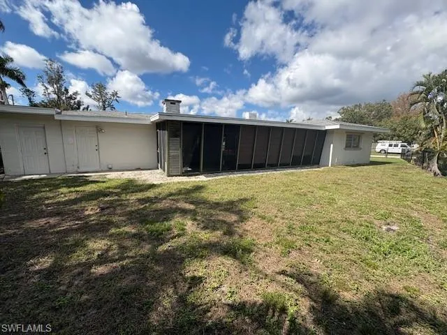 Back of property with a sunroom and a lawn