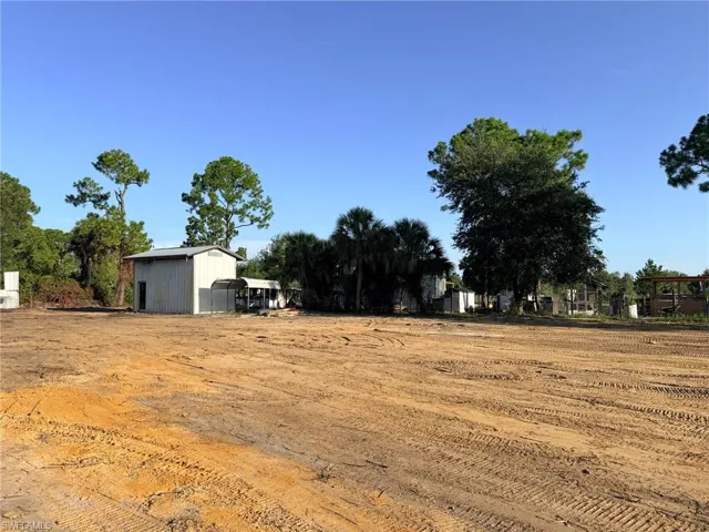 Cleared land with a metal outbuilding and surrounding mature trees
