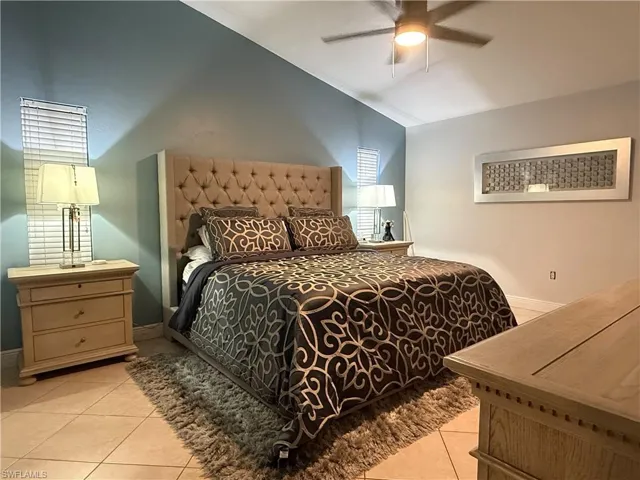 Vaulted ceiling with an attached ceiling fan, tiled flooring, and window blinds