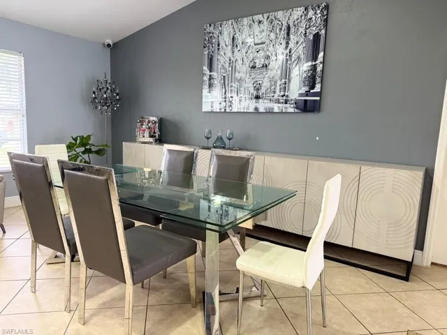 Tiled flooring, built-in storage cabinetry with decorative detailing, glass-top table, wall-mounted lighting fixture, and window with horizontal blinds