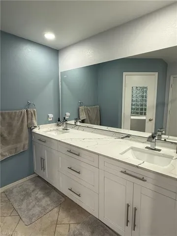 Dual vanity with undermount sinks, stone-finish countertop, and chrome fixtures