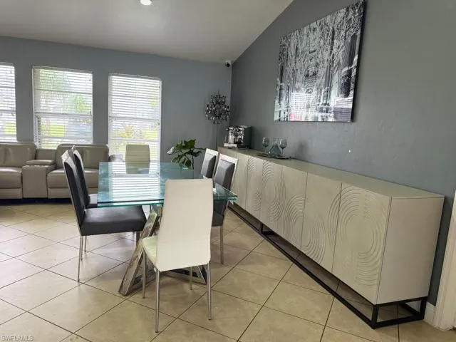 Expansive tile flooring, multiple windows with horizontal blinds, and a built-in credenza featuring decorative paneling