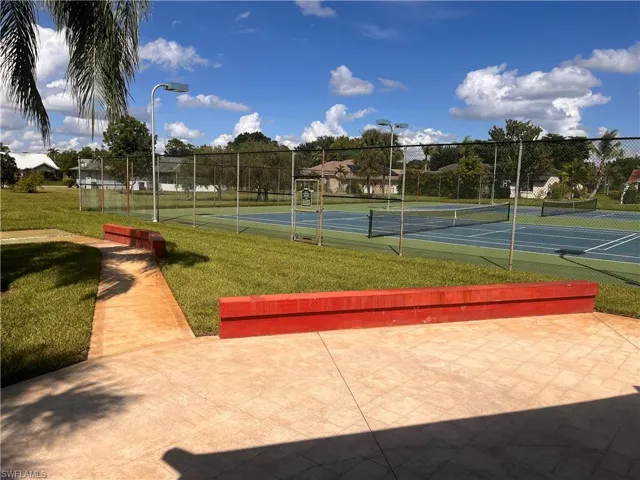 Two tennis courts with chain-link fencing and overhead lighting