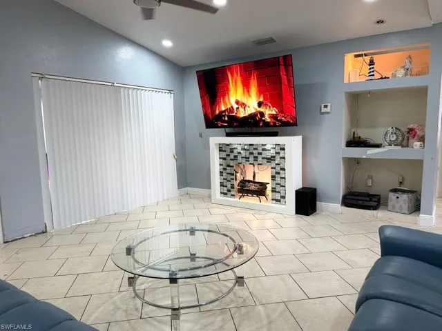 Tiled flooring throughout, built-in wall shelving, recessed lighting, and vertical window blinds