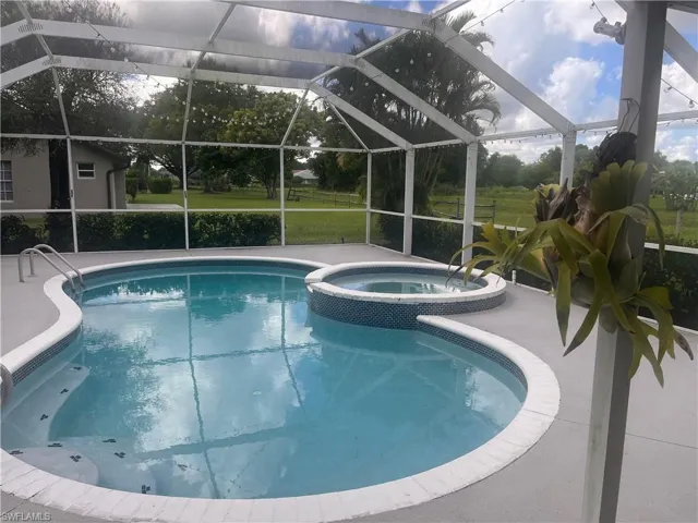 Screened enclosure with a freeform pool, integrated spa, and surrounding hardscaping