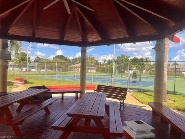 Covered gazebo with wood-finish decking, multiple picnic tables, and concrete pathways