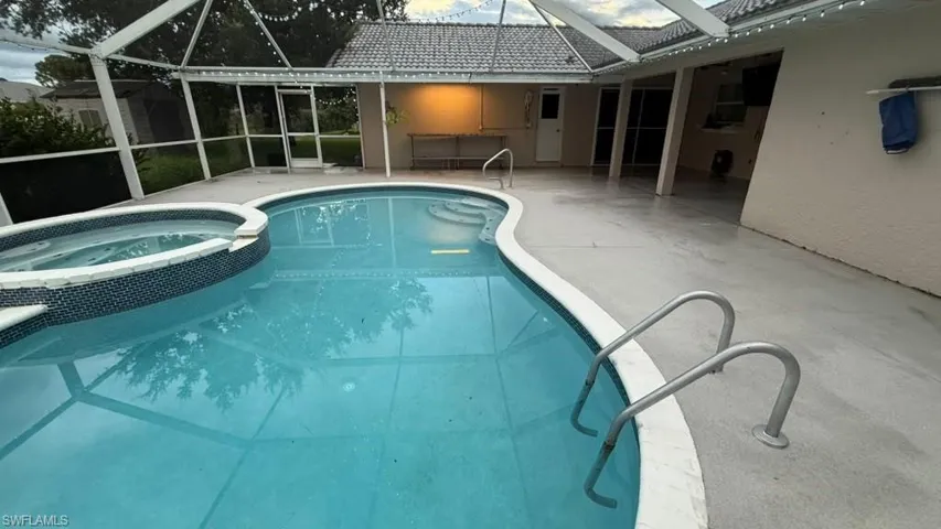 Screened enclosure featuring a contoured pool with integrated spa and tiled surround