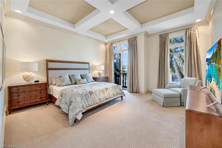 Carpeted bedroom with beamed ceiling, coffered ceiling, and access to outside