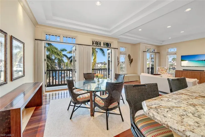Dining area with dark wood finished floors, a tray ceiling, ornamental molding, and recessed lighting