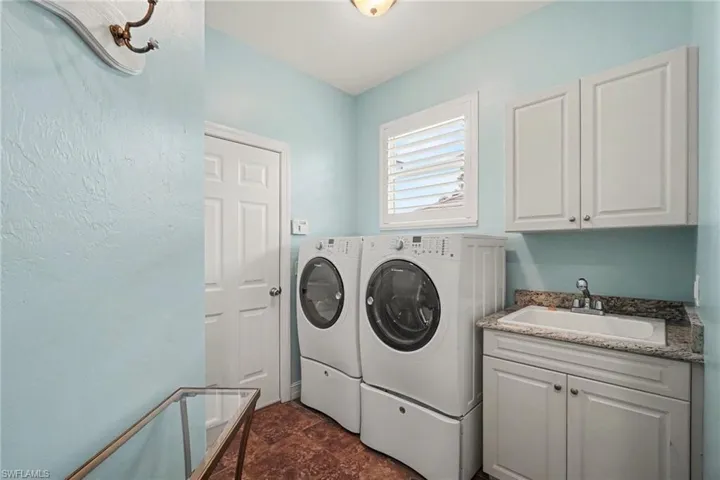 Spacious laundry room with sink, storage cabinets, and closet