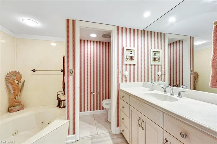 Bathroom with vanity, wallpapered walls, a jetted tub, light tile patterned flooring, and recessed lighting