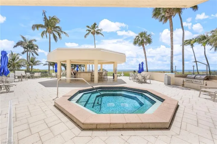 View of pool with exterior kitchen, a community hot tub, a water view, a pool, and a patio