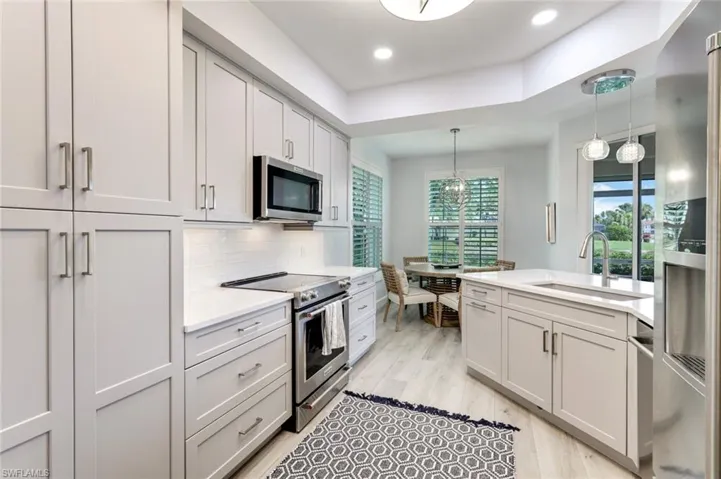 Beautiful shaker style cabinetry with clean white backsplash, tray ceiling and recessed lighting!