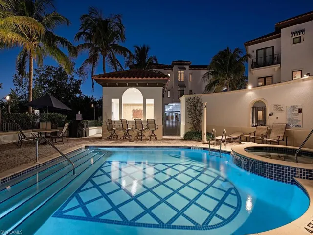 Pool at night with a pool with connected hot tub and a patio