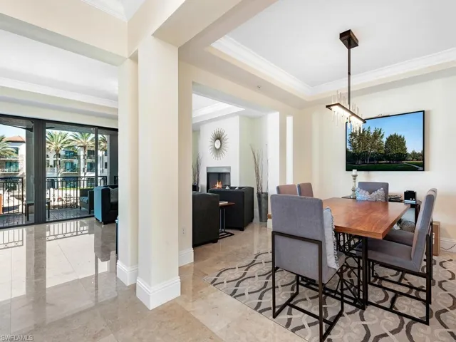 Dining room with a warm lit fireplace, crown molding, a chandelier, and a tray ceiling