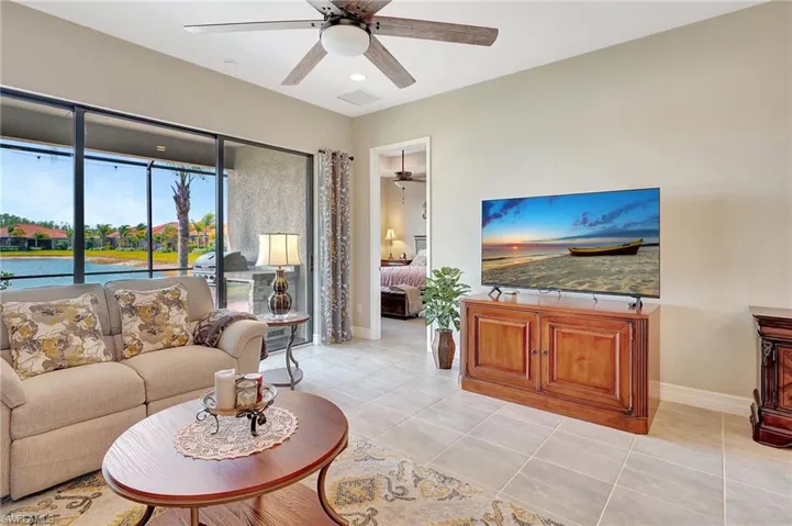 Living room featuring baseboards, visible vents, light tile patterned floors, and a ceiling fan