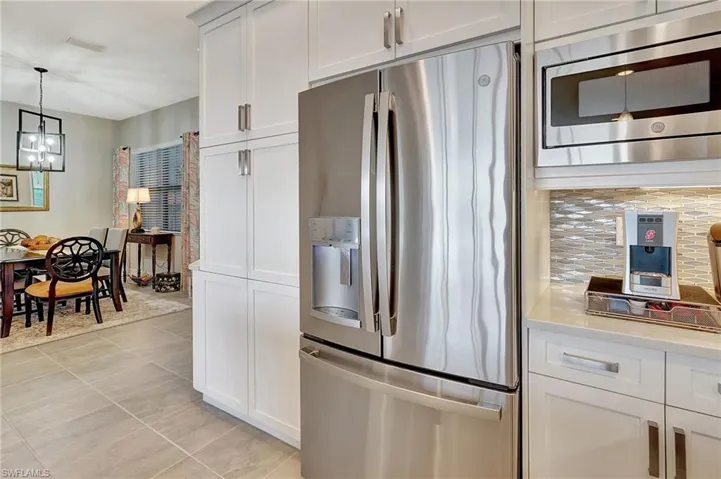 Kitchen with light countertops, a chandelier, appliances with stainless steel finishes, hanging light fixtures, and visible vents