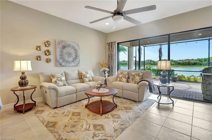 Tiled living area with baseboards, a water view, recessed lighting, and a ceiling fan