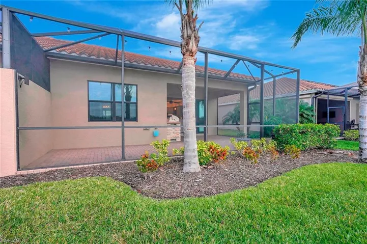 Rear view of property with stucco siding, a patio, a tiled roof, glass enclosure, and a lawn