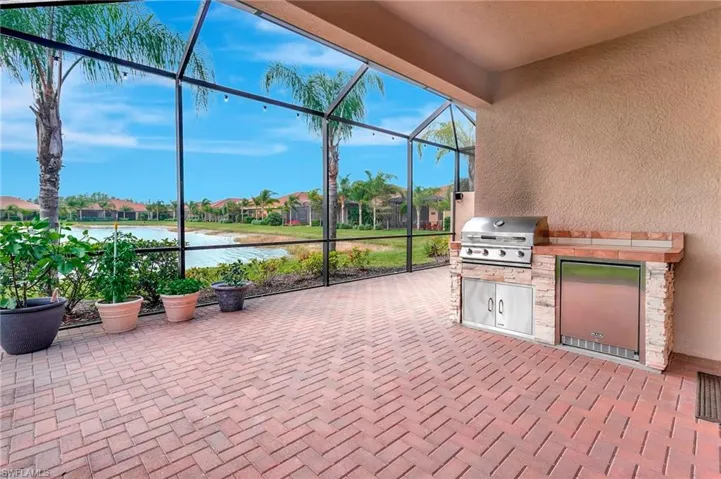 View of patio featuring glass enclosure, an outdoor kitchen, and area for grilling