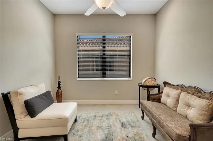 Living area with light tile patterned flooring, baseboards, and a ceiling fan