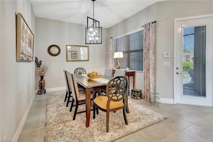 Tiled dining area with baseboards and a notable chandelier