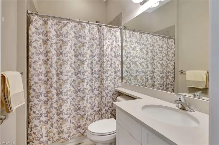 Full bath with curtained shower, toilet, and vanity