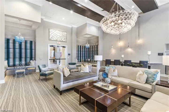 Living area featuring a chandelier, carpet, baseboards, ornamental molding, and a high ceiling