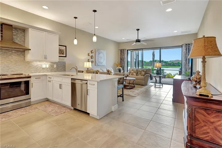 Kitchen featuring light countertops, a peninsula, wall chimney exhaust hood, tasteful backsplash, and appliances with stainless steel finishes