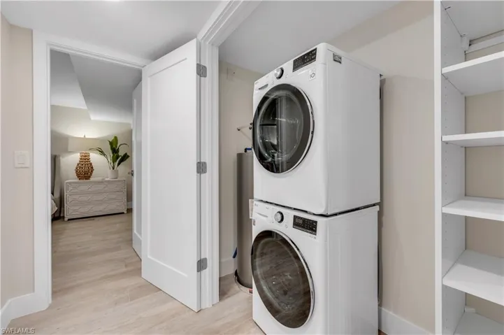 Clothes washing area featuring light wood-type flooring and stacked washer / drying machine