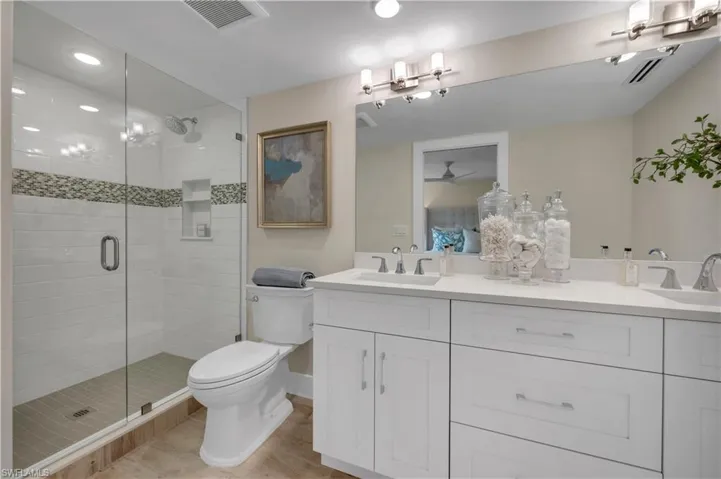 Bathroom featuring double vanity, an enclosed shower, and toilet