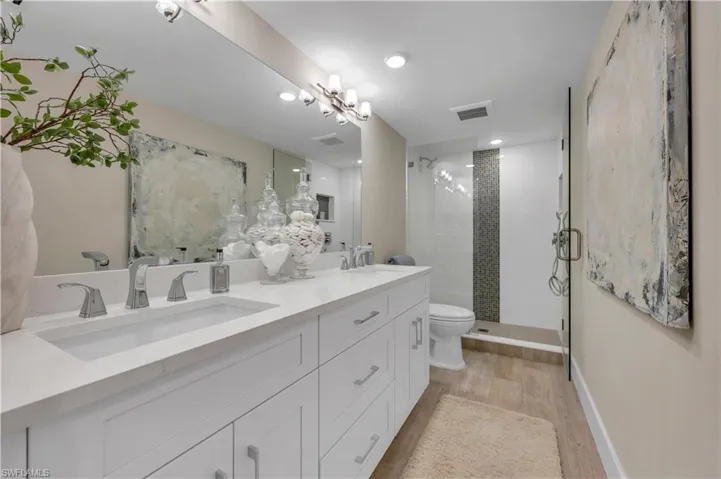 Bathroom with double sink, an enclosed shower, hardwood / wood-style flooring and large vanity