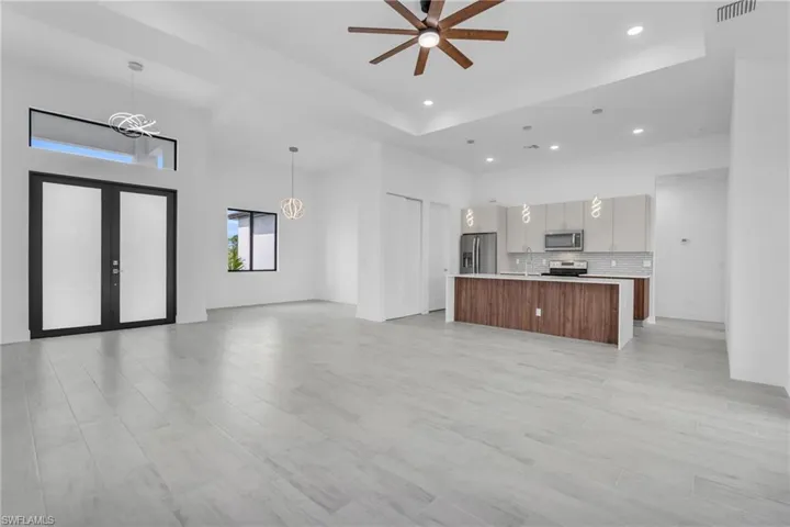 Unfurnished living room with french doors, ceiling fan, recessed lighting, light wood finished floors, and a high ceiling
